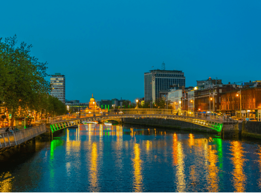 Image of the hapenny bridge in Dublin with lights reflecting off the river liffey