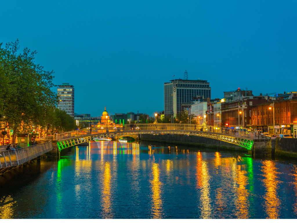 Image of the hapenny bridge in Dublin with lights reflecting off the river liffey