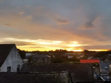 Image of sun setting over rooftops in Ennis.